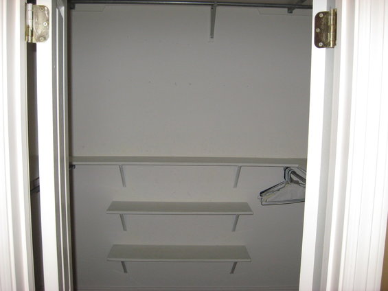 Interior of a white closet with a metal rod and three shelves. A single empty hanger is visible