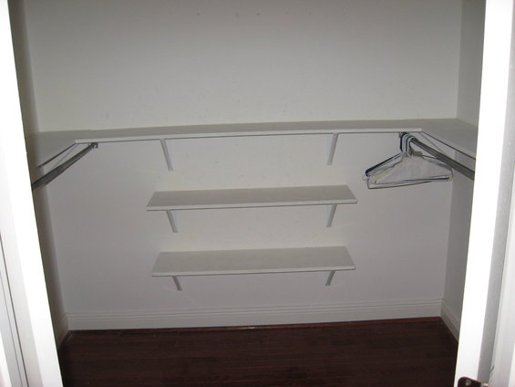 Empty closet interior with white shelves and a metal hanging rod