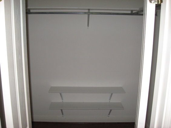 Empty closet with a metal hanging rod and two white shelves