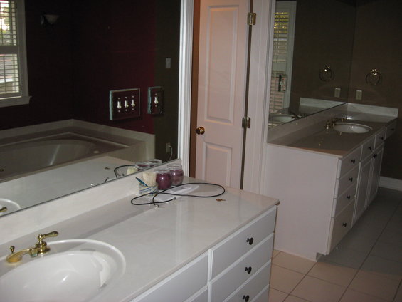 Bathroom with a large mirror reflecting a tub, double vanity, and a door