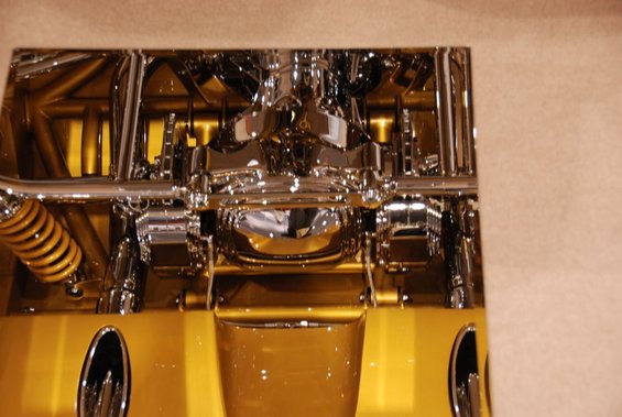 Close-up of polished chrome suspension and drivetrain parts on a gold vehicle