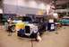 1996 Ford Bronco - A model kit box for a 1940 Ford Sedan is displayed alongside several vintage vehicles at an indoor event.