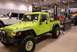 1996 Ford Bronco - A lime green Jeep Brute pickup truck is displayed indoors next to a white Jeep Wrangler.