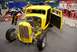 1996 Ford Bronco - Yellow hot rod on display indoors, showing its engine and custom build.
