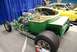 1996 Ford Bronco - A custom green hot rod is displayed indoors with a yellow muscle car in the background.
