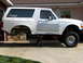 1996 Ford Bronco - A white SUV is elevated on jack stands, revealing its undercarriage and suspension components.