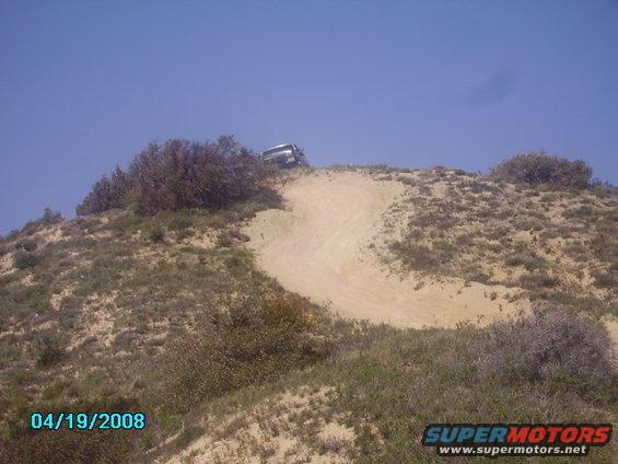 SUV climbing a sandy hill with a dirt track
