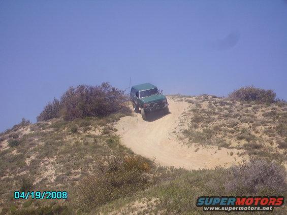 Green SUV driving down a dirt hill, front-right quarter view