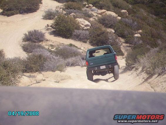 Green Ford Bronco with lifted suspension on a dirt trail