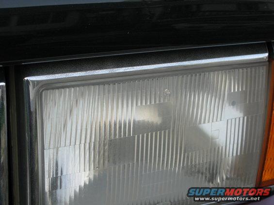 Close-up of a clear headlight lens with vertical fluting and chrome trim