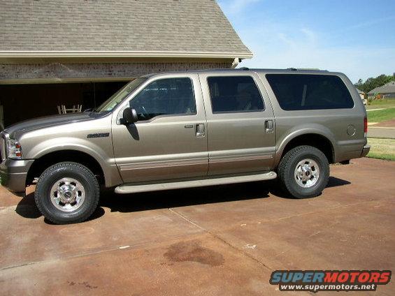 Tan Ford Excursion SUV parked on a driveway, side view