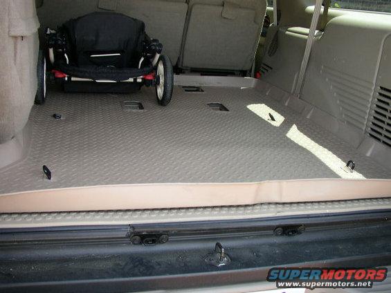 Interior cargo area of an SUV with a folded stroller and tie-down hooks