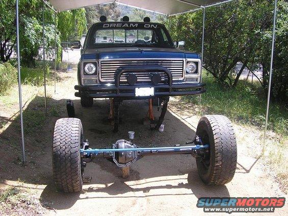 Front of a dark blue pickup truck, lifted with front axle removed. "DREAM ON" is written on the windshield