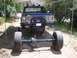 1979 Chevrolet C/K Pickup - This pickup truck is elevated on jacks with its front axle removed, revealing the undercarriage and large tires.