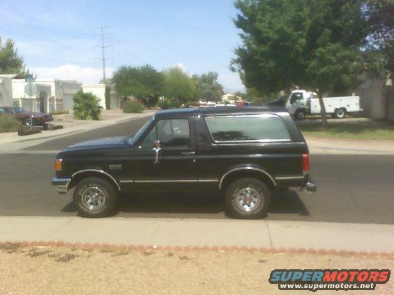 Side view of a black 1989 Ford Bronco parked on a sidewalk