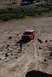 1995 Ford Bronco - A red 1995 Ford Bronco navigates a dusty, rocky terrain with tire tracks visible.