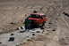 1995 Ford Bronco - A red 1995 Ford Bronco is parked on a dirt road with a person standing near the front.