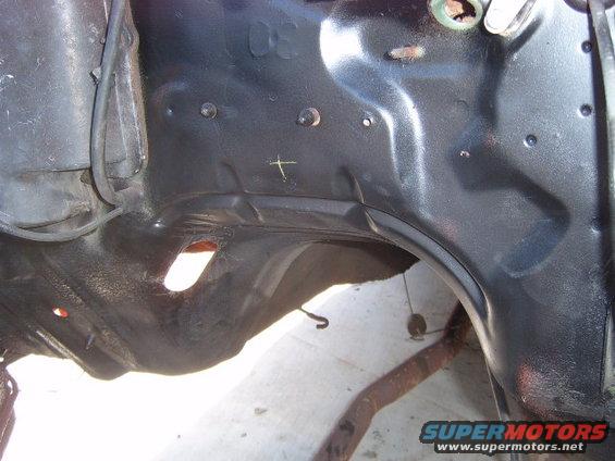 Black painted vehicle frame section with holes and a rusty exhaust pipe visible