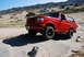 1995 Ford Bronco - A red 1995 Ford Bronco is parked on a dirt mound in a dry, hilly area with RVs visible in the distance.