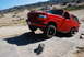 1995 Ford Bronco - A red Ford Bronco navigates an off-road obstacle course with other vehicles and RVs in the background.