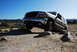 1995 Ford Bronco - GMC Yukon XL navigates rocky terrain under a clear blue sky.