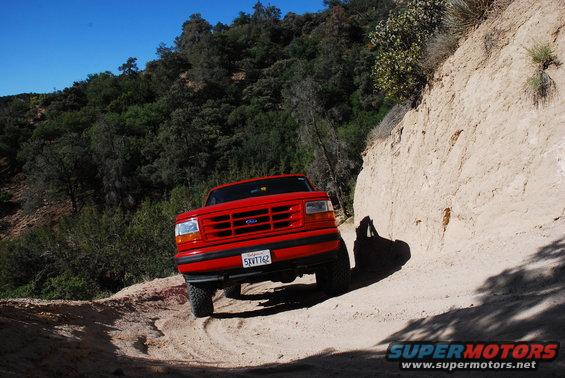 Red 1992 Ford F-150 truck on a dirt road, front view