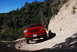 1995 Ford Bronco - A red 1992 Ford F-150 navigates a dusty trail under a clear blue sky.