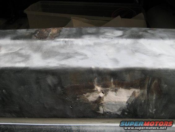 metal body panel being prepped for repair, showing rust and filler