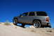 1995 Ford Bronco - Silver SUV navigates a rocky off-road trail under a bright blue sky.