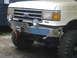 1989 Ford Bronco - Front view of a white Ford truck a chrome bumper with a winch and auxiliary lights.