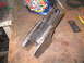 1979 Ford Bronco - A custom-welded metal component rests on a workbench, alongside a welding helmet and measuring tape.
