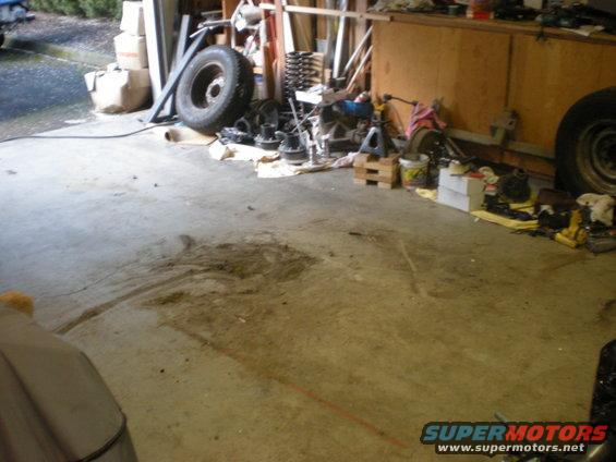 Garage floor with scattered vehicle parts including a tire, springs, and axles