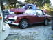 1973 MG Midget - A maroon 1973 MG Midget convertible is parked outdoors next to a red pickup truck.