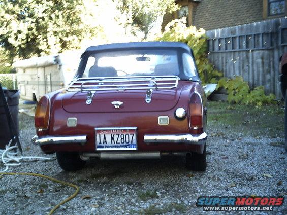 Rear view of a red 1973 MG Midget convertible with a luggage rack and Idaho license plate