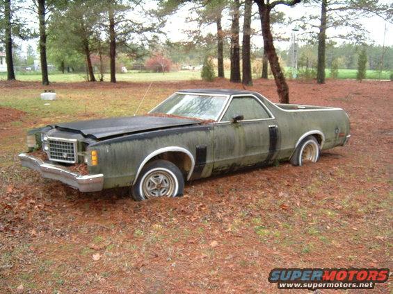 1979 Ford Ranchero, green, with flat tires, parked in a wooded area