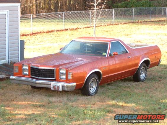 Orange Ford Ranchero parked on grass next to a shed