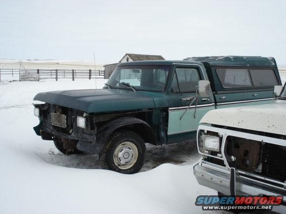 Green and teal 1979 Ford F-150 pickup truck with camper shell in snow
