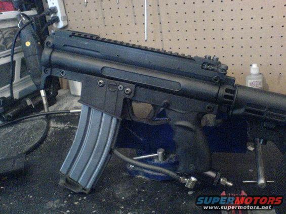 Black rifle with magazine and air hose attached, clamped in a vise