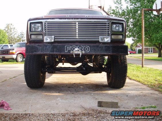 1980 Ford Bronco front view with custom bumper and lifted suspension. Another Ford truck is visible to the left