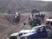 1988 Ford Bronco - A group of off-road vehicles navigate a challenging, rocky landscape, with one vehicle overturned.