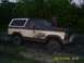 1982 Ford Bronco - A muddy 1980s Ford Bronco is stuck in a dirt track with a person standing nearby.