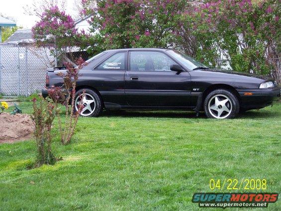 Black coupe with GT badge parked on lawn. Has a sticker on the rear window