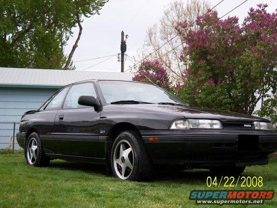 Black 1989 Mazda MX-6 GT coupe parked on grass, front 3/4 view