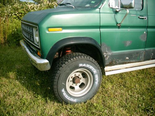 Green van front corner with chrome bumper, visible rust spots, and "DAKOTA H/T FUTURA" tire
