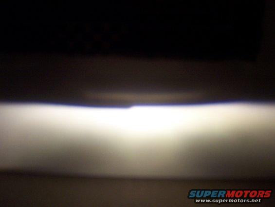 Headlight beam illuminates a dark surface with a bright horizontal band