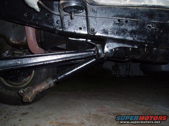 Undercarriage of a vehicle with black painted frame, driveshaft, and exhaust pipe. Tire visible on left