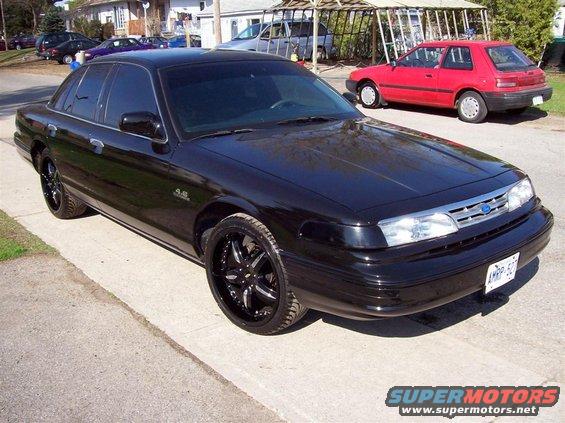 Black sedan with aftermarket rims parked on a street, showing a "4.6" badge on the fender