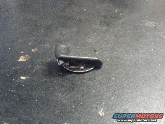 Black plastic part with a metal clip attached to a circular base