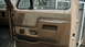 1990 Ford Bronco - Interior door panel detail of a truck, possibly from the 1990s, a two-tone fabric insert and a pull handle.