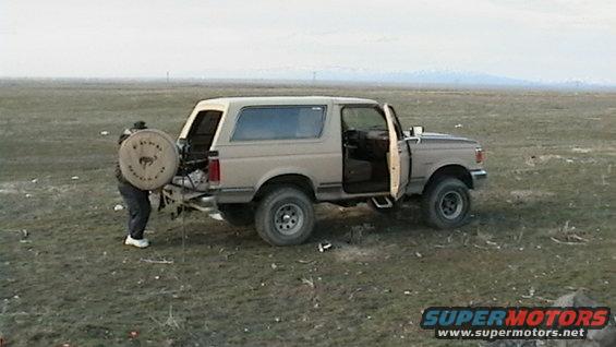 Tan 1990 Ford Bronco with doors open and spare tire carrier
